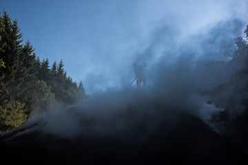 Traditional Charcoal Worker.  Silhouette of wood charcoal maker at work on a pile of slow burning wood. This is the traditional way of producing charcoal.
