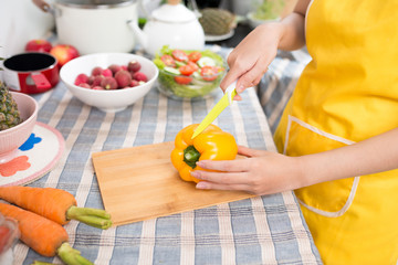 Cute asian woman slicing a pepper in her kitchen