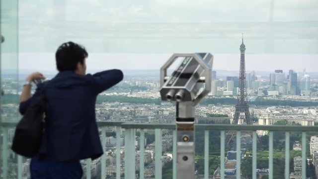 Male Tourist Enjoys Panoramic View Of Paris From Montparnasse Tower. The Montparnasse Tower Panoramic Observation Deck has the most beautiful view of Paris.