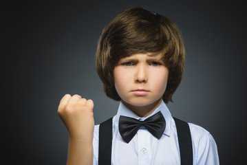 Portrait of angry boy isolated on gray background. He raised his fist to strike. Closeup