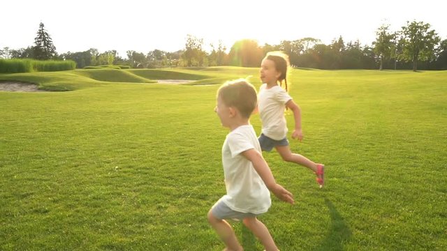 Active leisure. Running children. Summer happy kids time. Contre-jour Backlight. Flares flecks of sunlight. Slow motion video footage.