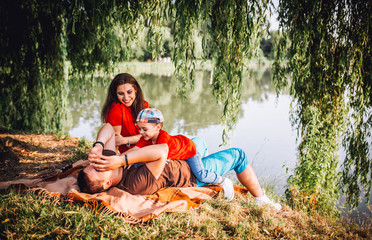 family resting and fun on plaid neat the lake. Summer meadow. Top view. Copy space. hand of child on eye.