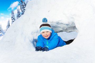 Little boy crawl through snow tunnel in park