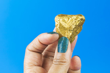 Female Hand Holding Gold Nugget on Blue Background