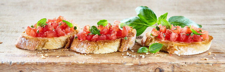 Delicious tomato bruschetta slices on a board - obrazy, fototapety, plakaty