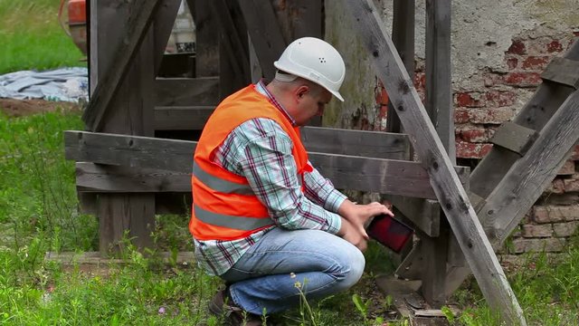 Construction worker checking wooden scaffolding and take pictures on tablet PC