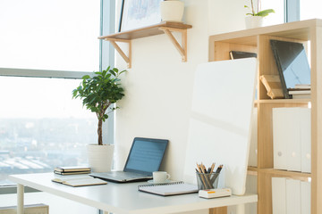Side view picture of studio workplace with blank notebook, laptop. Designer comfortable work table, home office.