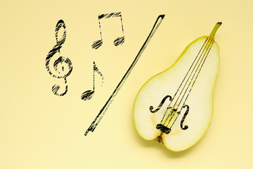 Sweet music / Creative concept photo of a pear as a violin with illustrated bow and notes on yellow background.