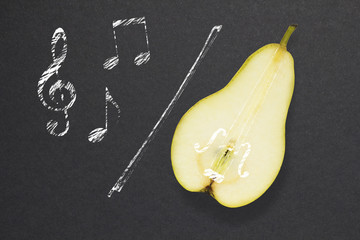 Sweet music / Creative concept photo of a pear as a violin with illustrated bow and notes on black...