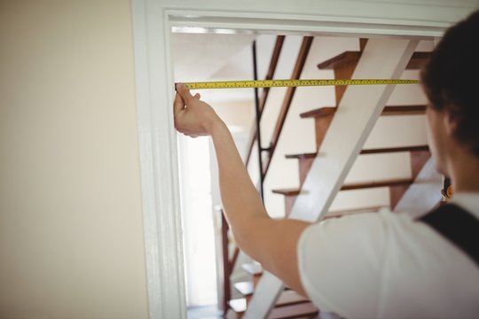 Carpenter Measuring A Door Frame