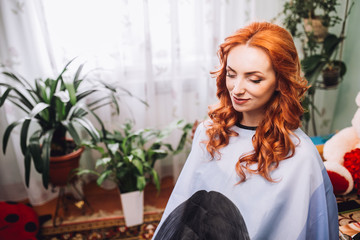 Makeup artist preparing bride before the wedding in a morning. Red hair woman. Hairdresser.