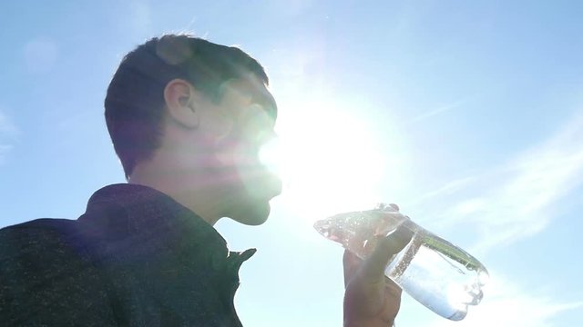 Young sportsman drinking water from a bottle on the stadium, slow motion