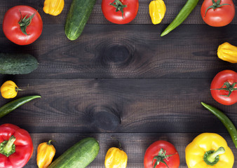 Fresh vegetables on wooden table. Red and yellow peppers, cucumber chilli and habanero peppers, tomatoes. Image with copy space.