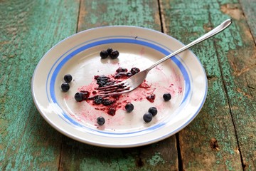 Dirty plate with fresh crushed blueberries on turquoise background