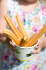 Girl in flower dress holding churros in a cup
