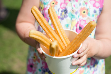 Girl in flower dress holding churros in paper cup