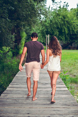 Fototapeta premium Couple holding hands and walking on the pier