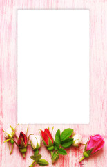 Obraz na płótnie Canvas empty frame greeting label rose buds on a pink wooden background in retro style shabby chic top view