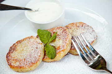 cheesecake slice decorated with mint leaf and sauce on white plate