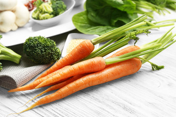 Carrots with vegetables and spices on wooden table