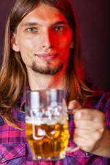 Man holds glass of beer.