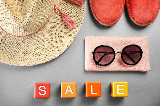 Red shoes, straw hat and sunglasses on grey background. Sale concept