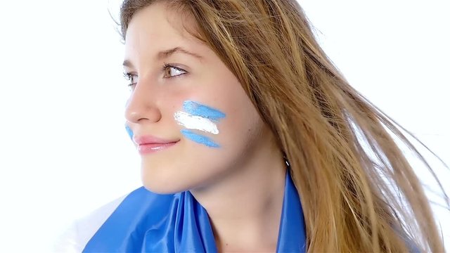 Girl with Argentinian flag on her face smiling, slow motion