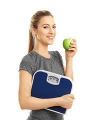 Beautiful young woman holding floor scales on white background
