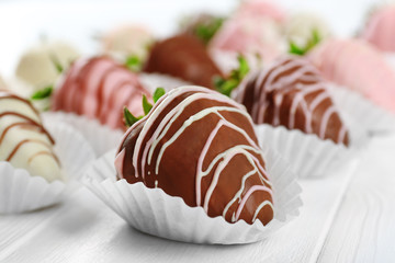 Tasty strawberries in chocolate on light wooden table