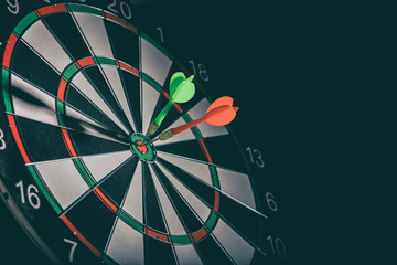 Two darts in the target center, bullseye, black background, copy space
