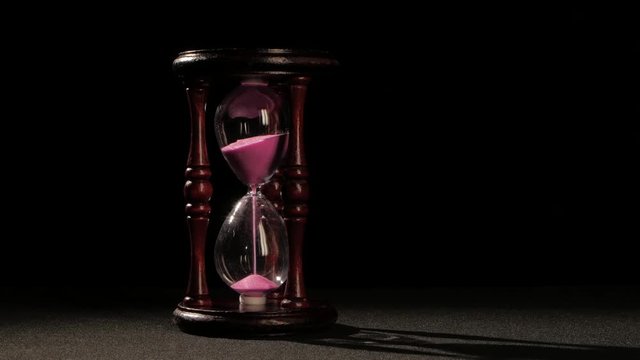 Countdown in the hourglass. Pink sand. Black