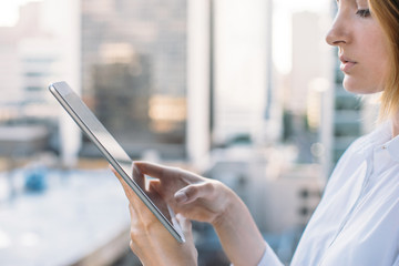 Close-up of young woman checks messages on the tablet, woman using digital tablet on city background, comfortable workplace, Shallow DOF.