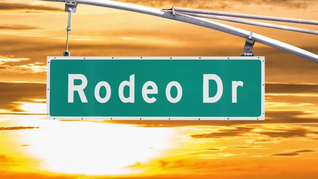 Rodeo Drive Beverly Hills sign with sunset time lapse sky.