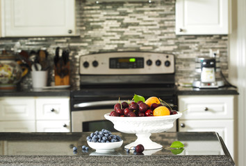 Fresh berries and fruits in vase on the kitchen table with grani