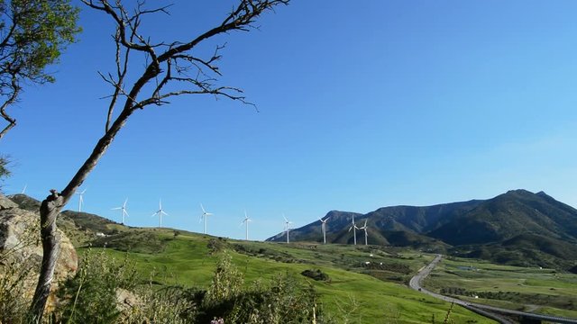 Landscape of green fields and mountains with wind turbines renewable energy moving