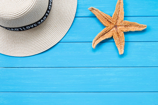 Straw hat and starfish on wood