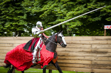 Armored knight on horseback charging in a joust with the lance raised. Jousting is a martial game...