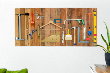Set of tools hanging on wood board on white wall
