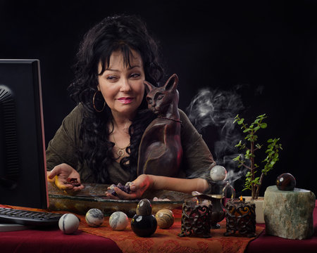 Fortune teller with gemstones looks at monitor