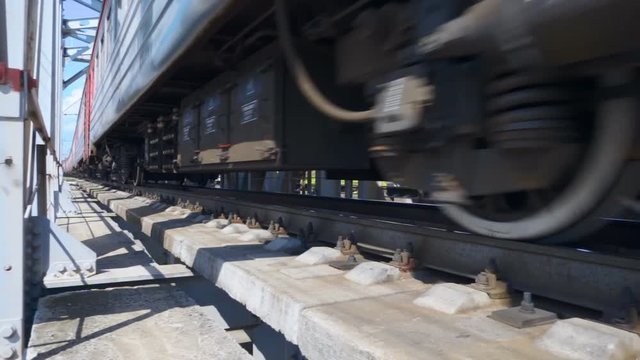 Closeup of wheels and other equipment under the carriage of the moving fast train. Slow motion, high speed camera, 250fps
