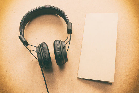 Headphone with brown and white paper note memo on wood desk in music room studio.