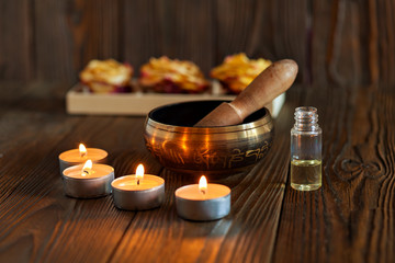 Singing bowl on dark wooden background. Burning candles and oil for aromatherapy and massage