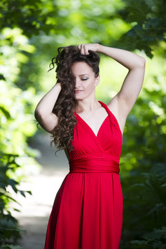 Beautiful young caucasian brunette woman in red dress outdoors