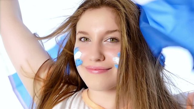 Girl waving Argentinian flag and smiling, slow motion