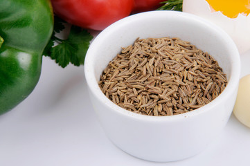 Cumin seeds in white bowl with vegetables