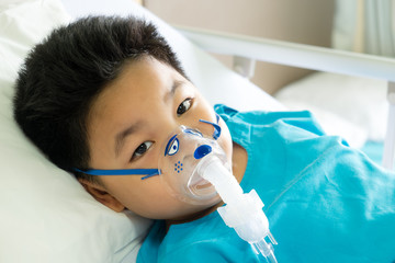 Boy wearing oxygen mask in hospital ward. Selective focus.
