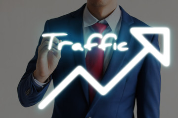 Businessman drawing TRAFFIC and upward graph arrows forward