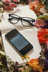 Creative composition with eyeglasse, mobile technology and books.