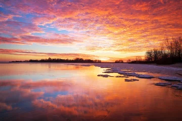 Tuinposter Beautiful winter landscape with sunset fiery sky and frozen lake © es0lex