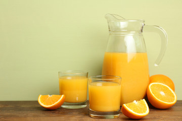 a carafe of orange juice on wooden  background with orange